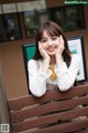 A woman sitting on a wooden bench with her hands on her face.