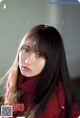 A woman with long black hair wearing a red sweater.