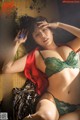 A woman in a green lingerie laying on a bed.