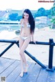 A woman in a silver bikini standing on a wooden dock.