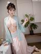 A woman in a pink and blue kimono sitting on a bed.