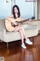 A woman sitting on a couch holding a guitar.