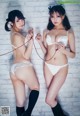 Two young women in white lingerie posing for a picture.