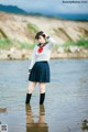 A woman in a school uniform standing in the water.