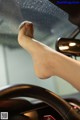 A woman's feet sticking out the window of a car.