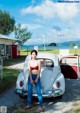 A woman in a red bikini standing next to a white car.