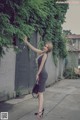 A woman in a black and white striped dress standing on a sidewalk.