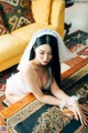 A woman in a wedding dress sitting on a rug.