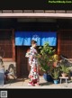 A woman in a kimono standing in front of a building.