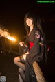 A woman in a kimono holding a sparkler.