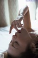 A woman laying on top of a bed with her eyes closed.