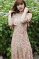 A woman in a pink floral dress posing for a picture.