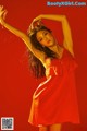 A woman in a red dress dancing on a red background.