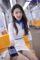 A woman sitting on a yellow bench holding a cell phone.