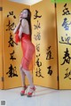 A woman in a red dress standing in front of a yellow wall.