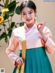 A woman in a pink and green hanbok poses for a picture.