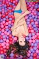 A woman in a blue bikini laying in a ball pit.