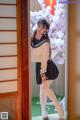 A woman in a sailor outfit standing in front of a door.