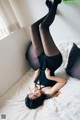 A woman laying on top of a bed in black stockings.