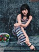 A woman sitting on the steps of a building next to a potted plant.